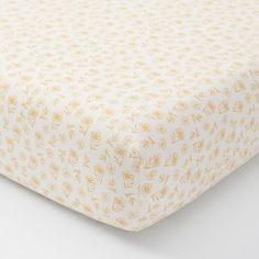 an image of a baby crib sheet that is yellow and has flowers on it