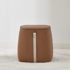 a brown ottoman sitting on top of a white rug