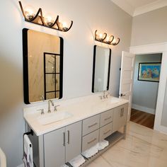 a bathroom with two sinks, mirrors and lights on the wall above them is shown