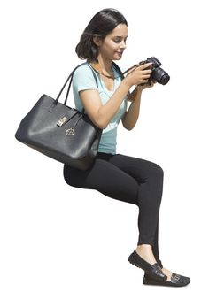 a woman holding a camera and jumping in the air with her legs spread wide open