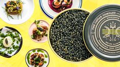 several plates and bowls filled with food on top of a yellow table