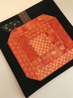 an orange and black patchwork piece on a white table