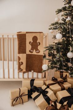 presents under a christmas tree in front of a crib with a teddy bear on it