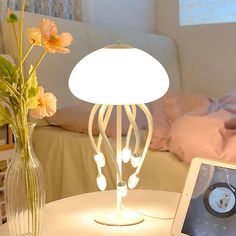 a tablet is sitting on a table next to a vase with flowers and a lamp