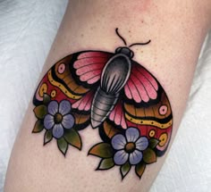 a butterfly tattoo with flowers on the side of her leg, and an insect sitting on top of it