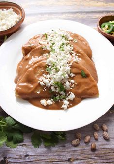 two enchiladas on a white plate topped with cheese and cilantro