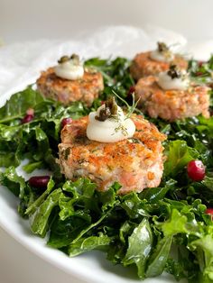 two crab cakes on top of a bed of green leafy salad with cranberries