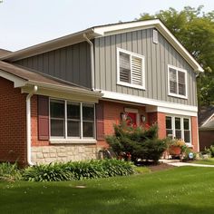 a red brick house with green grass and trees