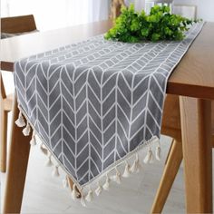 a dining room table with a gray and white runner