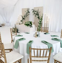 the table is set with white linens and green napkins for guests to sit at