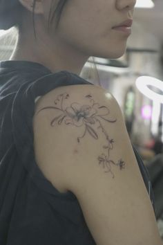 a woman with a flower tattoo on her arm and shoulder, looking off into the distance