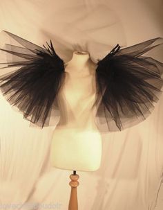 a mannequin with black tulle on it's head and wings hanging from the top