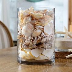 a glass container filled with sea shells on top of a wooden table