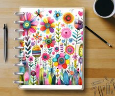 a notebook with colorful flowers on it next to a cup of coffee