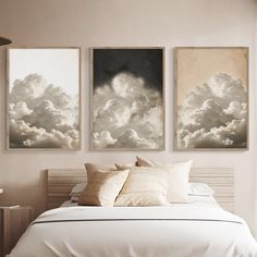 two paintings on the wall above a bed in a room with white sheets and pillows