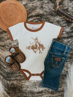 a baby's outfit, hat and shoes are laid out on the ground