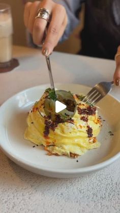 a woman is cutting into some food on a plate with a knife and fork in front of her