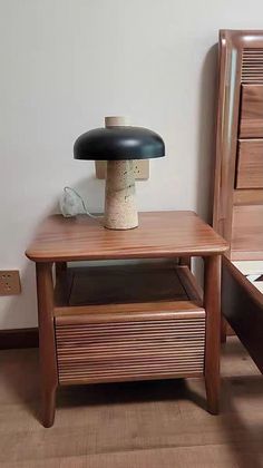 a wooden table with a lamp on top of it next to a bed and nightstand