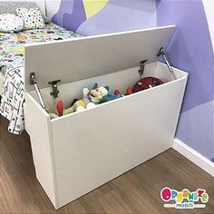 a toy storage box is open on the floor in front of a child's bed