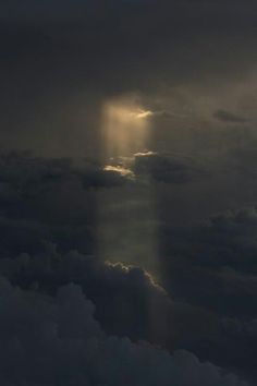 the sun shines through dark clouds as seen from an airplane