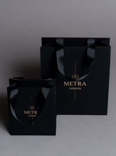 two black paper bags with gold lettering on them