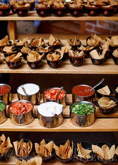 an assortment of food items displayed on shelves in a buffet style setting with chips and salsa