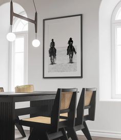 a black table with two chairs in front of it and a framed photo on the wall