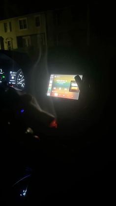 a person driving in the dark at night with their hand on the steering wheel and dashboard