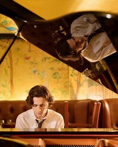 a man sitting at a table with a piano in front of him