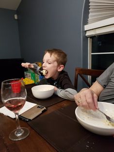 a man feeding a child food at a table