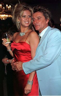 a man in a blue suit hugging a woman in a red dress at an event