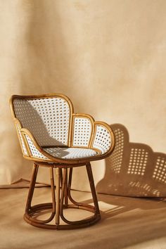 a wicker chair sitting on top of a wooden floor next to a white wall