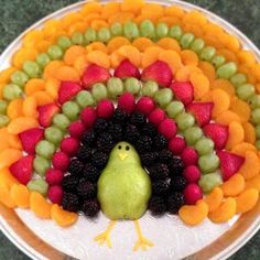 a turkey made out of fruits and vegetables on top of a white plate with a green bird