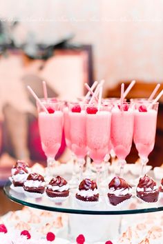 cupcakes and desserts are arranged on a glass platter with strawberries