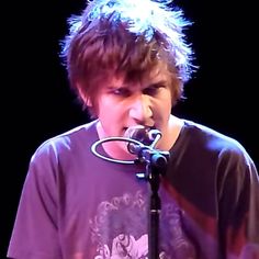 a young man singing into a microphone on stage