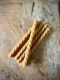 four yellow candles sitting on top of a wooden table next to twine string strings