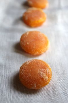 three oranges sitting on top of a white cloth next to each other in line