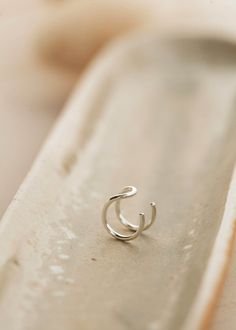 an open silver ring sitting on top of a white plate next to a piece of paper