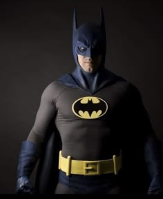 a man dressed as batman standing in front of a black background