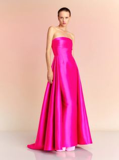 a woman in a bright pink gown poses for the camera with her hands on her hips