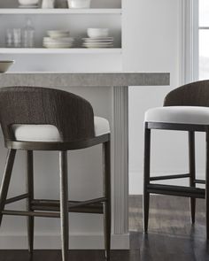 two bar stools sitting next to each other in front of a counter top with plates on it