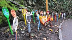 there are many colorful parking meters lined up on the side of the road with faces painted on them