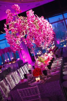 the centerpieces are decorated with pink flowers and candles in tall vases at the head table