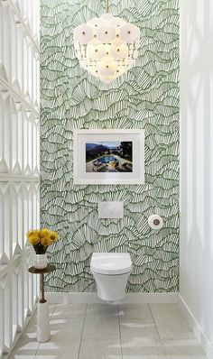 the bathroom is decorated in green and white with palm leaves on the wall behind it