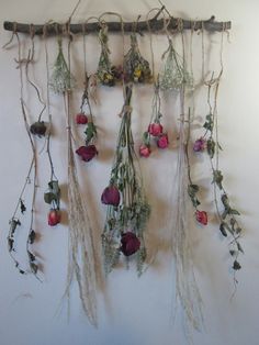 an arrangement of dried flowers hanging on a wall with vines and twigs attached to it