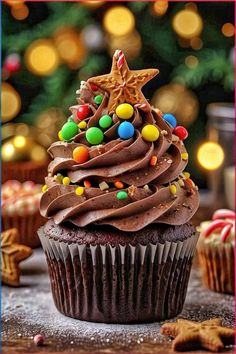 a cupcake with chocolate frosting and candies on the top, surrounded by christmas lights