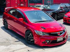 a red car is parked in front of other cars