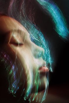 a blurry image of a woman's face with her eyes closed and hair blowing in the wind