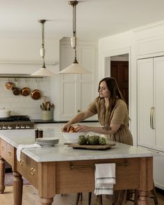 a woman standing at a kitchen island preparing food