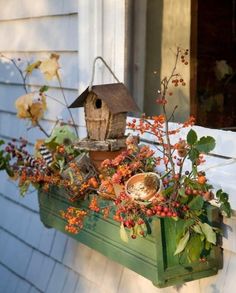 a bird house sitting on top of a window sill filled with flowers and berries